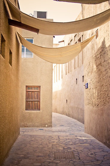 an alley way with stone walls and arched doorways in the center, leading to two buildings