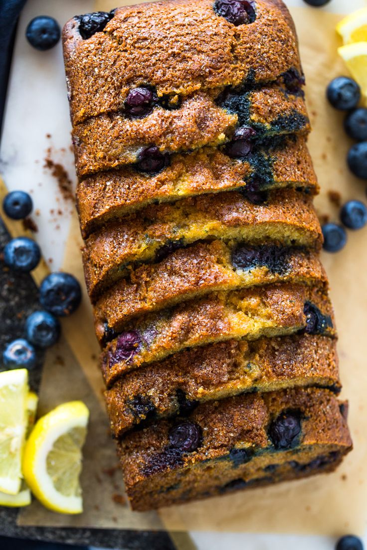 a loaf of blueberry lemon bread on a cutting board with sliced lemons next to it