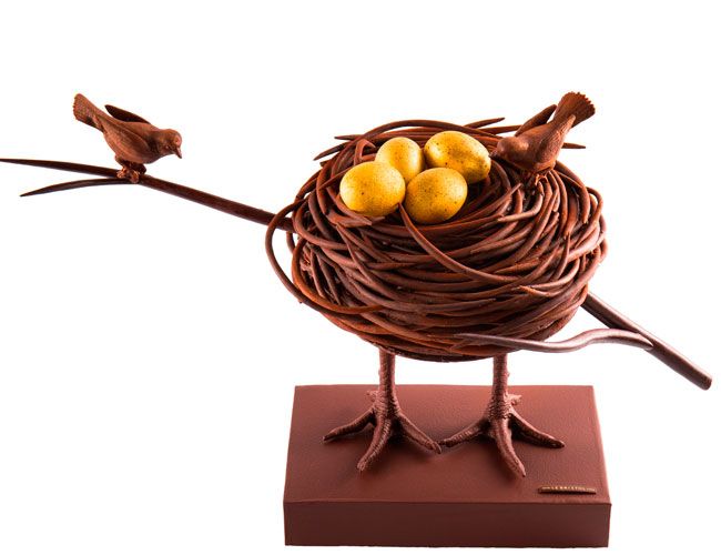 a bird nest with three yellow birds sitting on it's legs in front of a white background