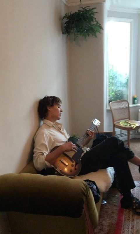 a person sitting on a couch with a guitar