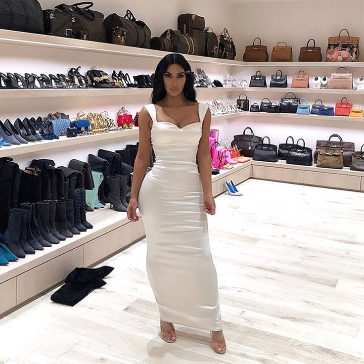 a woman standing in front of a display of handbags and purses at a shoe store