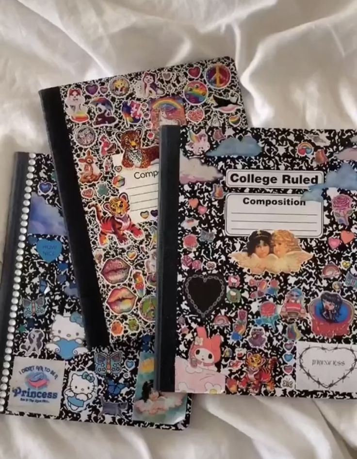 two notebooks sitting on top of a bed covered in stickers and writing paper