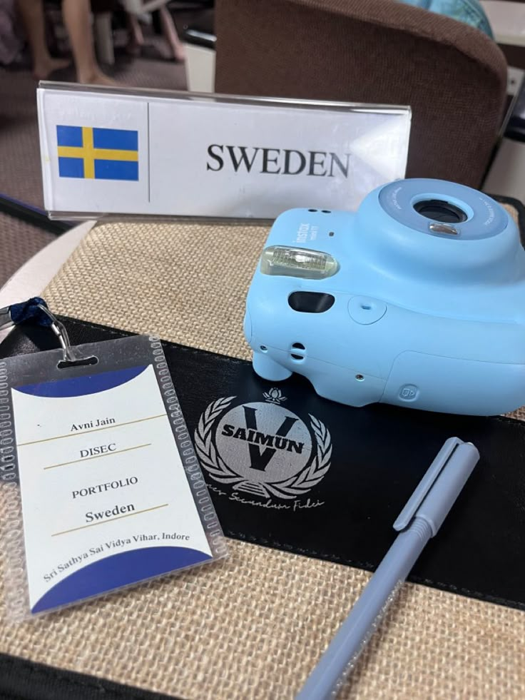 a blue camera sitting on top of a table next to a notepad and pen