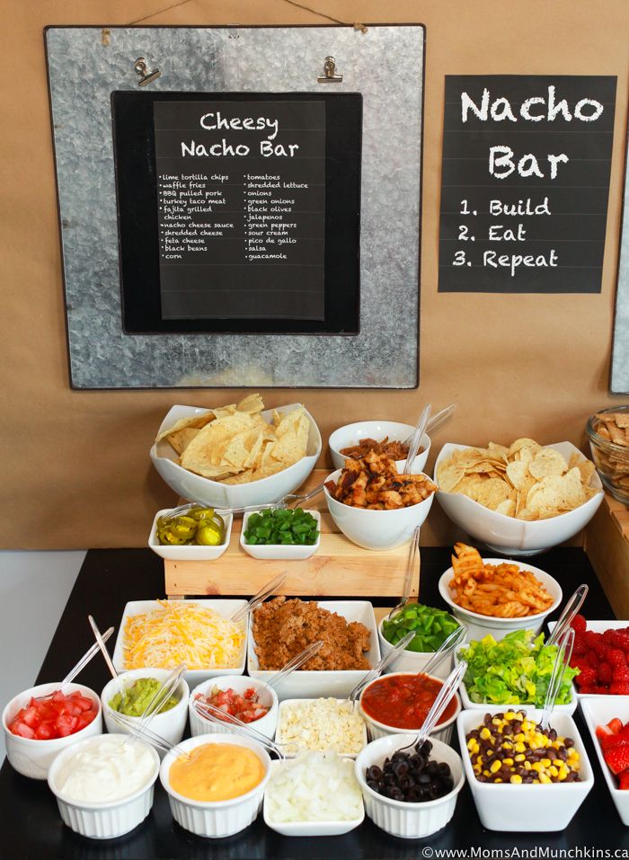 a table filled with lots of different types of food and drinks next to a chalk board