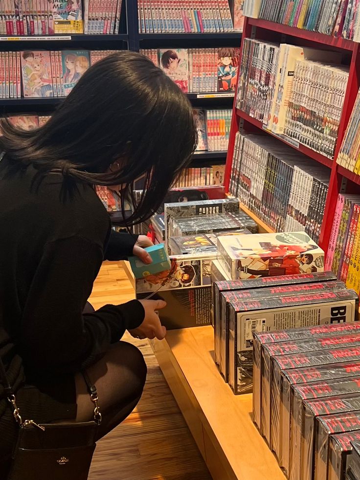 a woman kneeling down in front of a table filled with cds