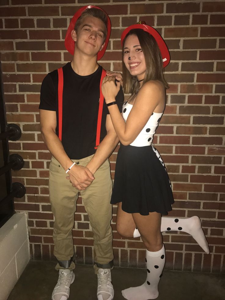 two people standing next to each other in front of a brick wall and wearing costumes