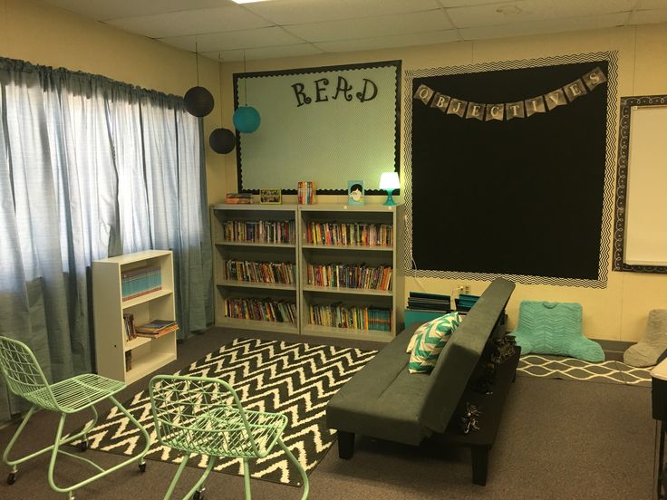 a room with bookshelves, chairs and a chalkboard on the wall in it