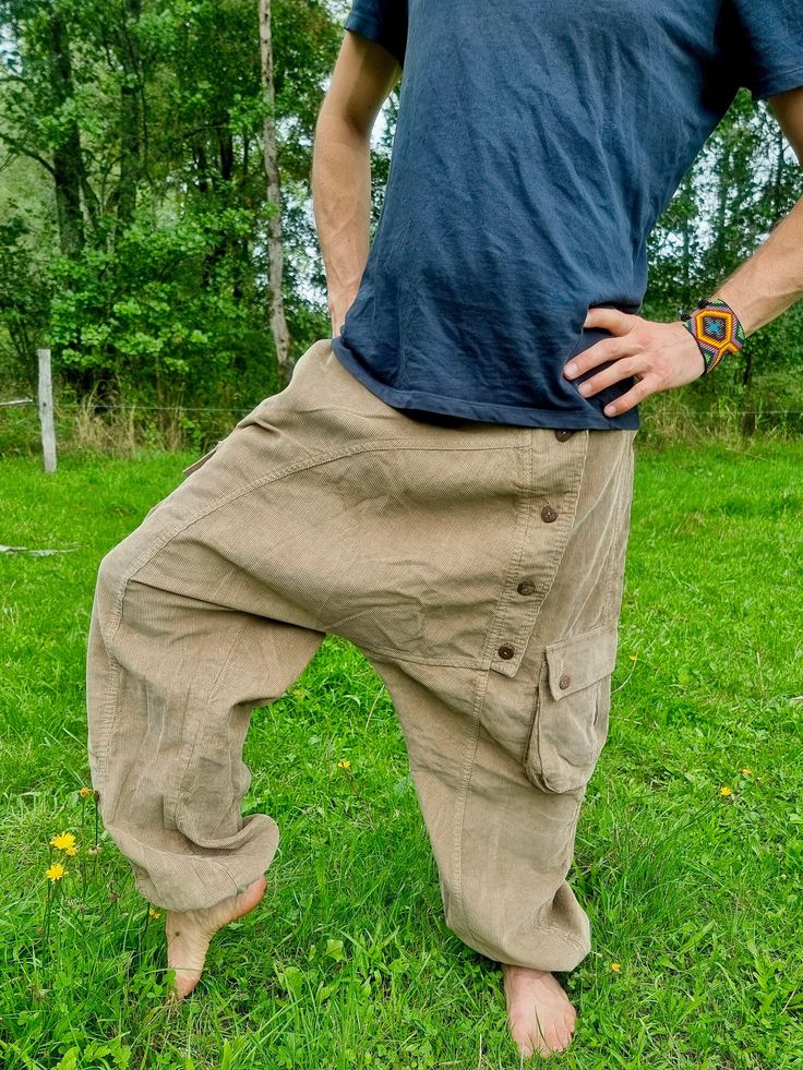 creme colored harempants out of heavy cord cotton fabric ॐ with two baggy bags and one regular pocket on the right leg. on the left leg is a raw of wooden buttons. it has an elastical waist band so it fits on perfect to your body. with the elastic bands on the ankles you can wear it as a short or 3/4 pants The trousers are all lovingly handcrafted individually by a small family business in Bangladesh <3 visually, this harem pants fits wonderfully with everything that is psychedelic, whether it's Baggy Beige Cotton Harem Pants, Beige Baggy Cotton Harem Pants, Baggy Hippie Harem Pants With Pockets, Brown Cotton Parachute Pants For Summer, Baggy Cotton Cargo Pants For Festival, Bohemian Festival Parachute Pants With Pockets, Bohemian Parachute Pants For Festivals, Bohemian Cotton Cargo Pants For Festivals, Cotton Parachute Pants With Pockets For Festivals