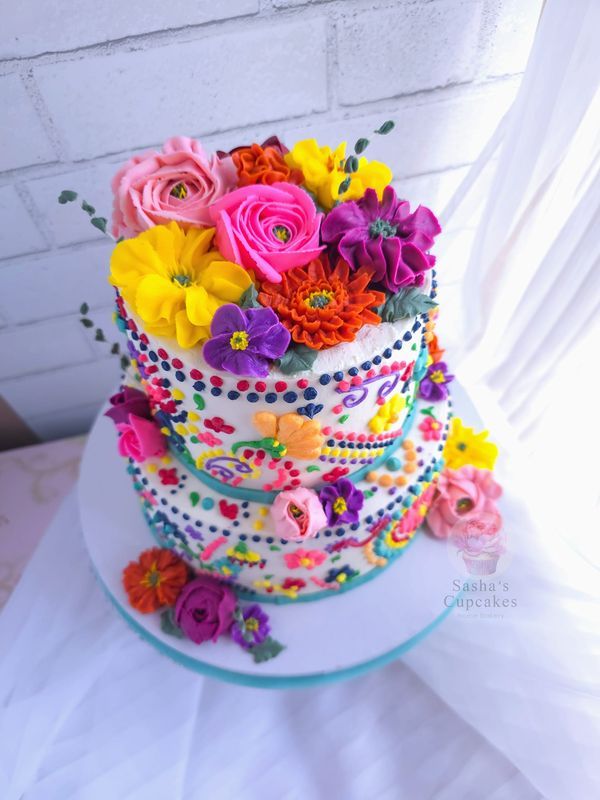 a multi layer cake decorated with flowers and beads on a white tableclothed surface