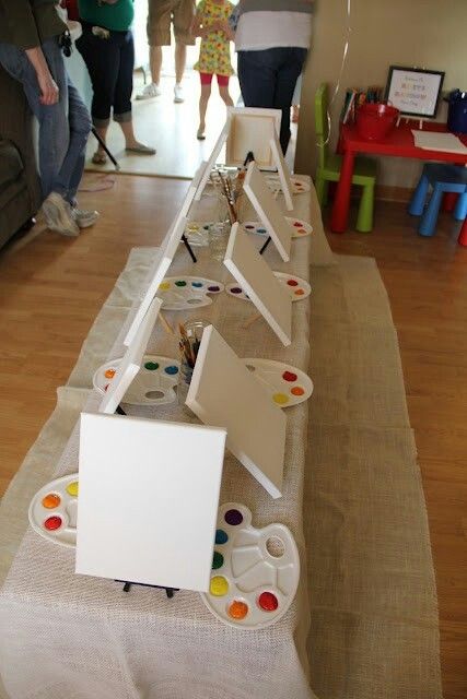 several people standing around a long table with art supplies on it