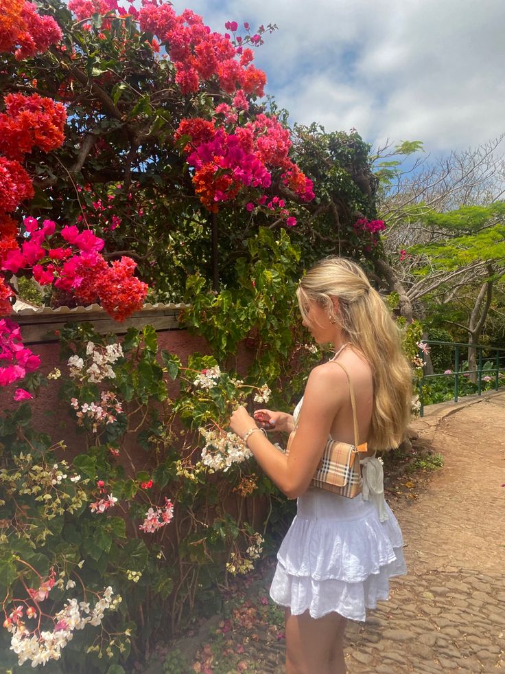 a woman is standing in front of some flowers