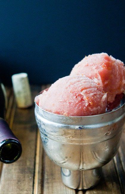 a metal bowl filled with ice cream next to a wine bottle