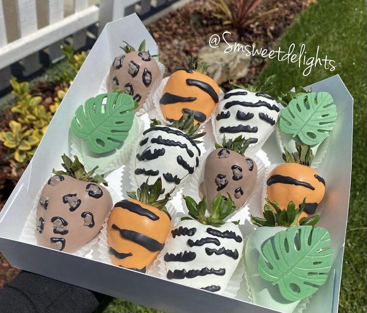 a box filled with chocolate covered strawberries on top of a green leafy plant