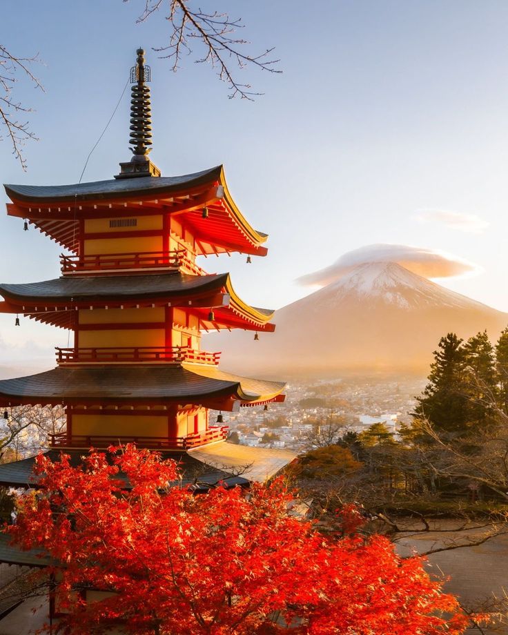 a tall red and yellow building sitting on top of a lush green field next to a mountain