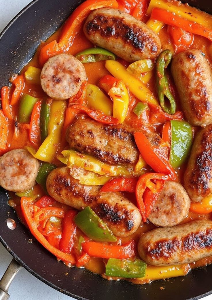 sausages and peppers are cooking in a skillet