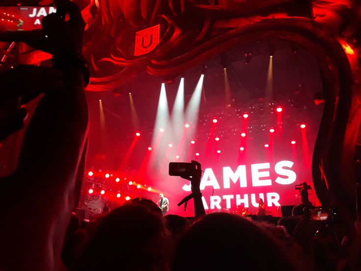 the stage is lit up with red and white lights, while people are taking pictures