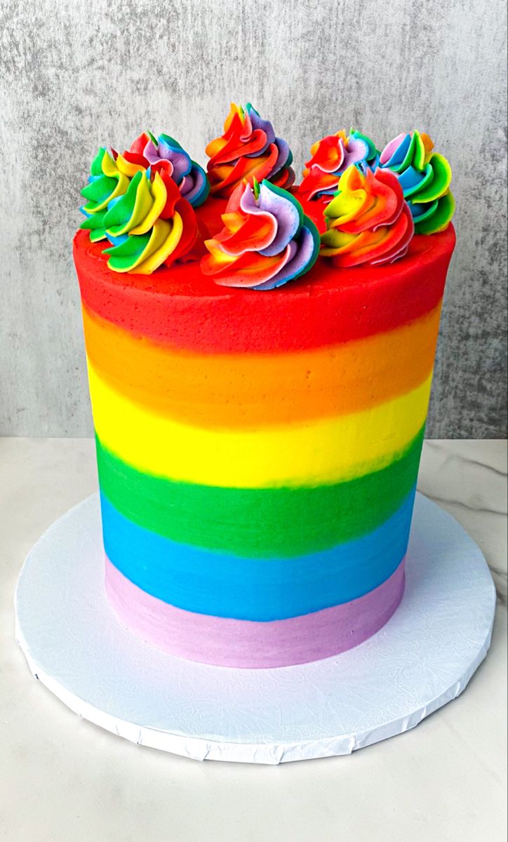 a rainbow cake with icing and sprinkles on top