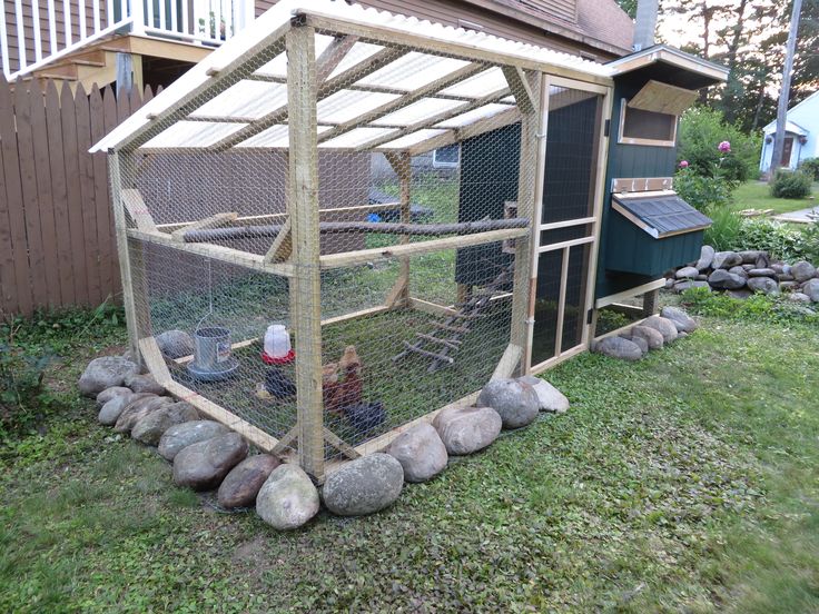 a chicken coop in the yard with rocks around it