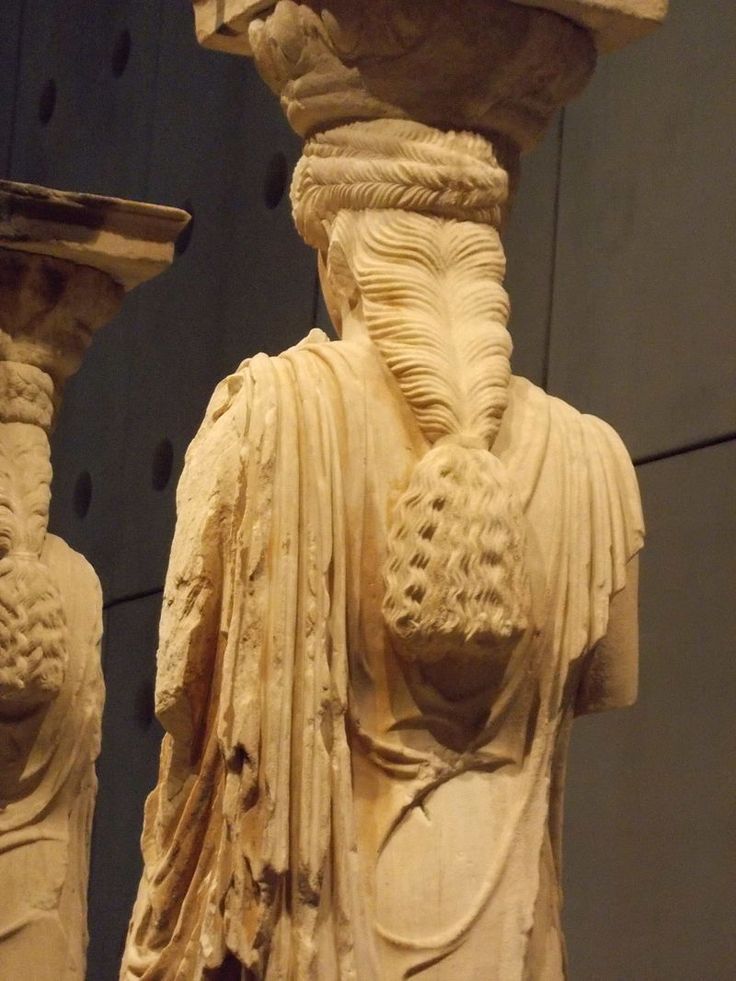 two statues of men with long hair and beards, one wearing a white dress