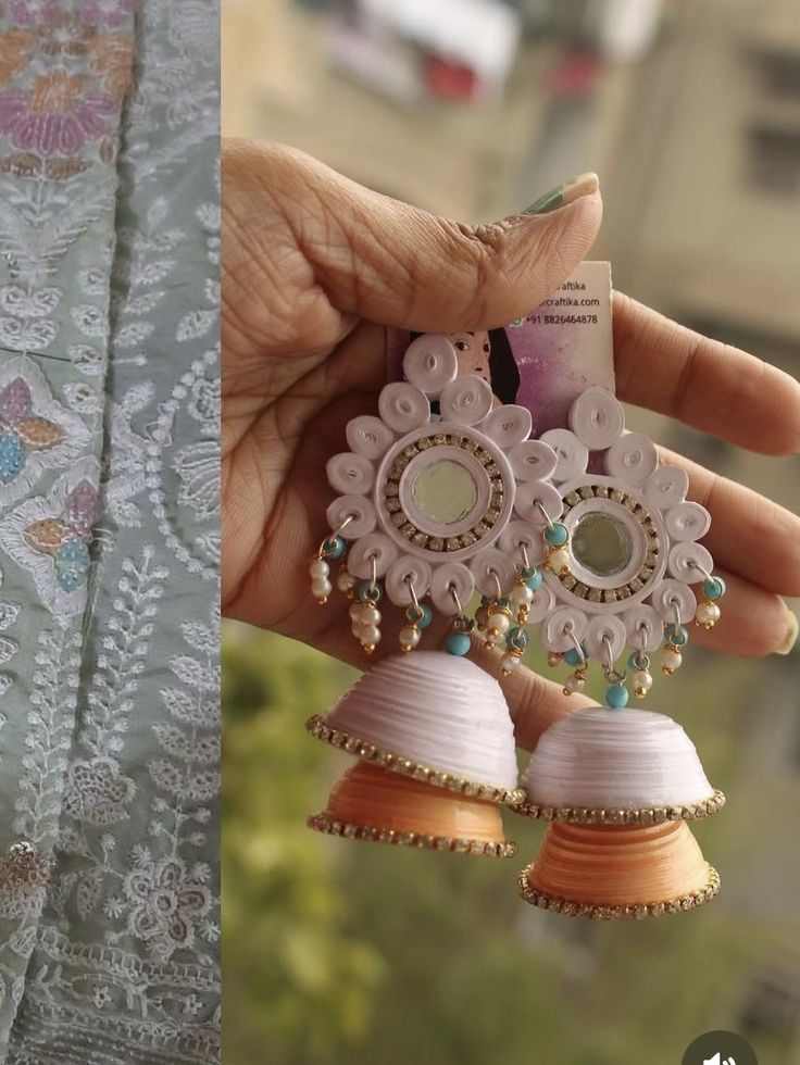 a woman holding two pairs of earrings in her hand next to an image of the same pair