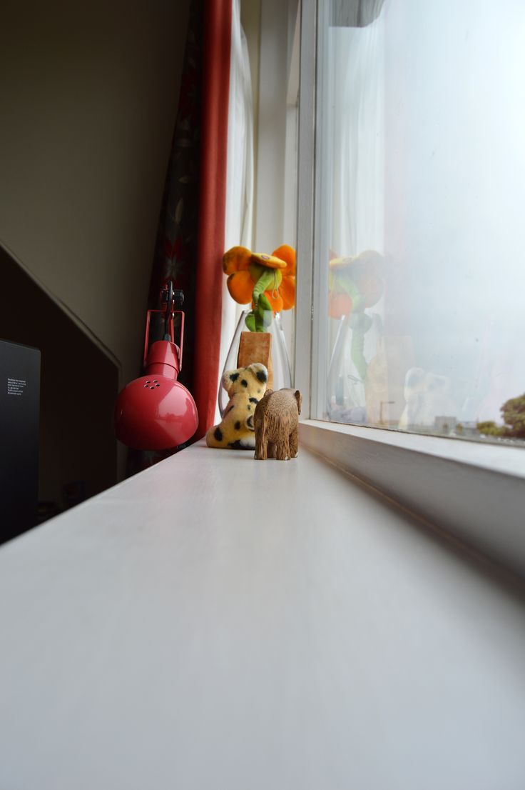 a small stuffed animal sitting on top of a counter next to a window sill