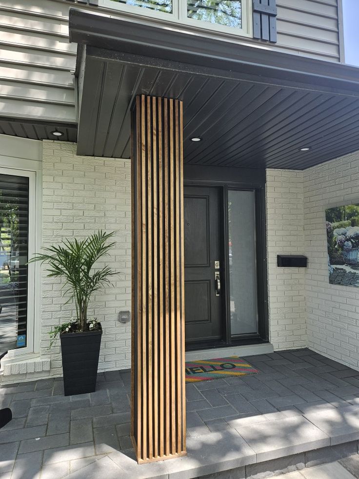 the front entrance of a house with a large wooden column and potted plant on the porch