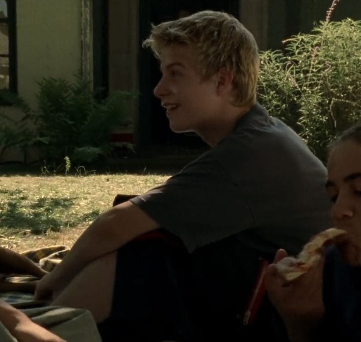 two people sitting on the ground eating pizza