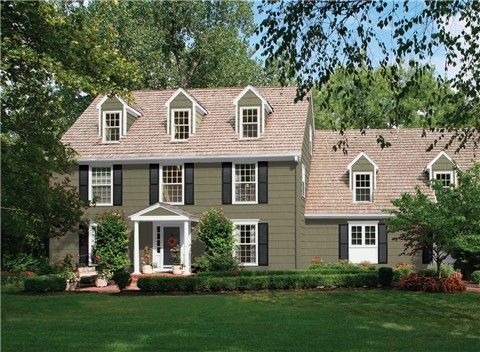 a large blue house with white trim and two story windows on the front, surrounded by lush green trees