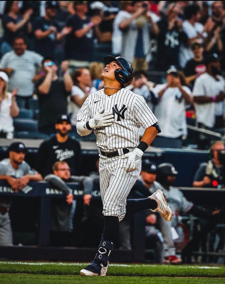 a baseball player running on the field in front of a crowd with his hands up