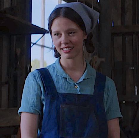 a woman wearing an apron and smiling for the camera