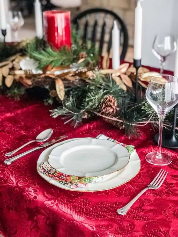 a red table cloth with white plates and silverware