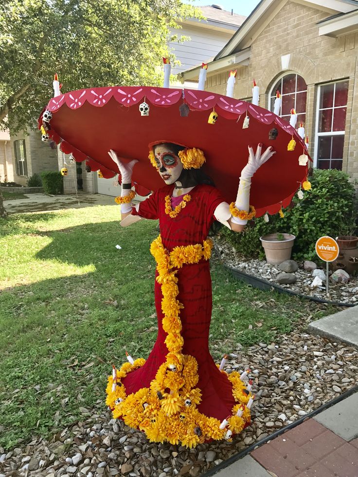 a woman dressed in red and yellow is holding an umbrella over her head while standing outside