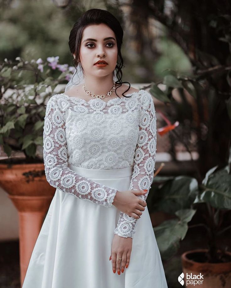 a woman in a white wedding dress standing next to a potted plant