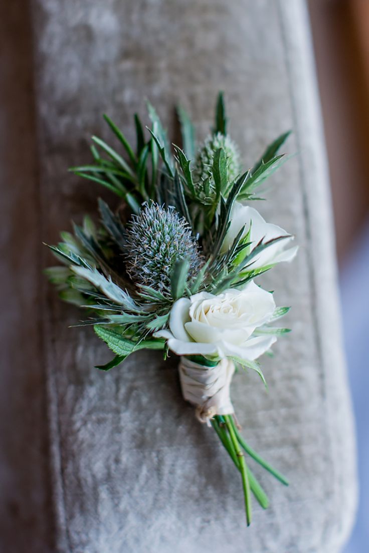 a boutonniere with white flowers and greenery on a gray chair cushion