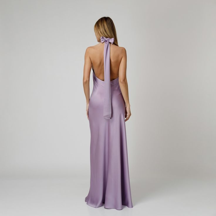 A captivating blend of elegance and allure, our Lylia Open Back Halter Dress exudes undeniable charm. Tailored with a flattering bias cut from lavender double silk satin, it drapes gracefully over the silhouette. The halter neckline delicately frames the shoulders, while the revealing back adds a note of sensuality. For a playful and feminine look, you can transform the silk tie neck into a chic bow, or you can let it drape loosely, adding a touch of laid-back sophistication to your ensemble.  W Lavender Fitted Maxi Dress For Evening, Fitted Lavender Maxi Dress For Evening, Elegant Purple Maxi Evening Dress, Fitted Lavender Dress For Gala, Purple Silk Maxi Dress For Gala, Elegant Purple Silk Evening Dress, Lavender Fitted Maxi Dress For Formal Occasions, Fitted Lavender Maxi Dress For Formal Occasions, Chic Lavender Maxi Dress For Formal Occasions