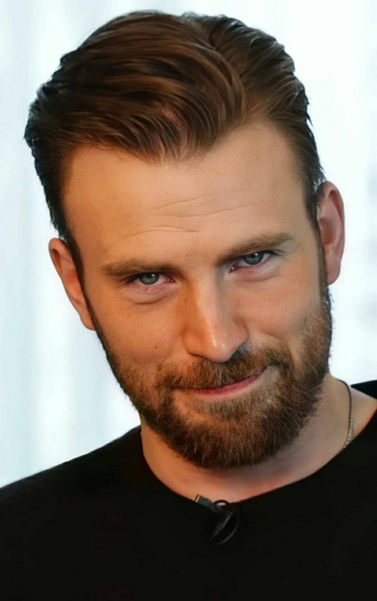 a close up of a person with a beard wearing a black shirt and looking at the camera