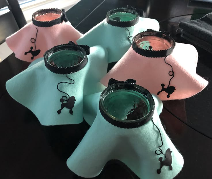 three glass vases sitting on top of a table with pink and blue cloth covering them