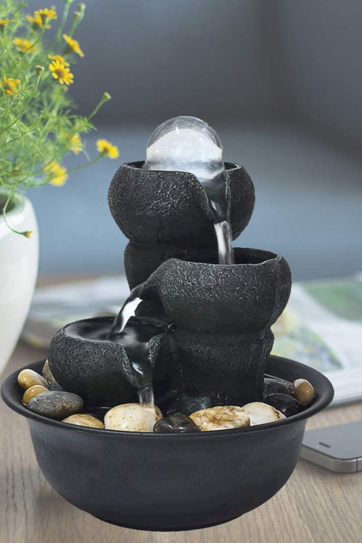 a black bowl with rocks and water pouring from it