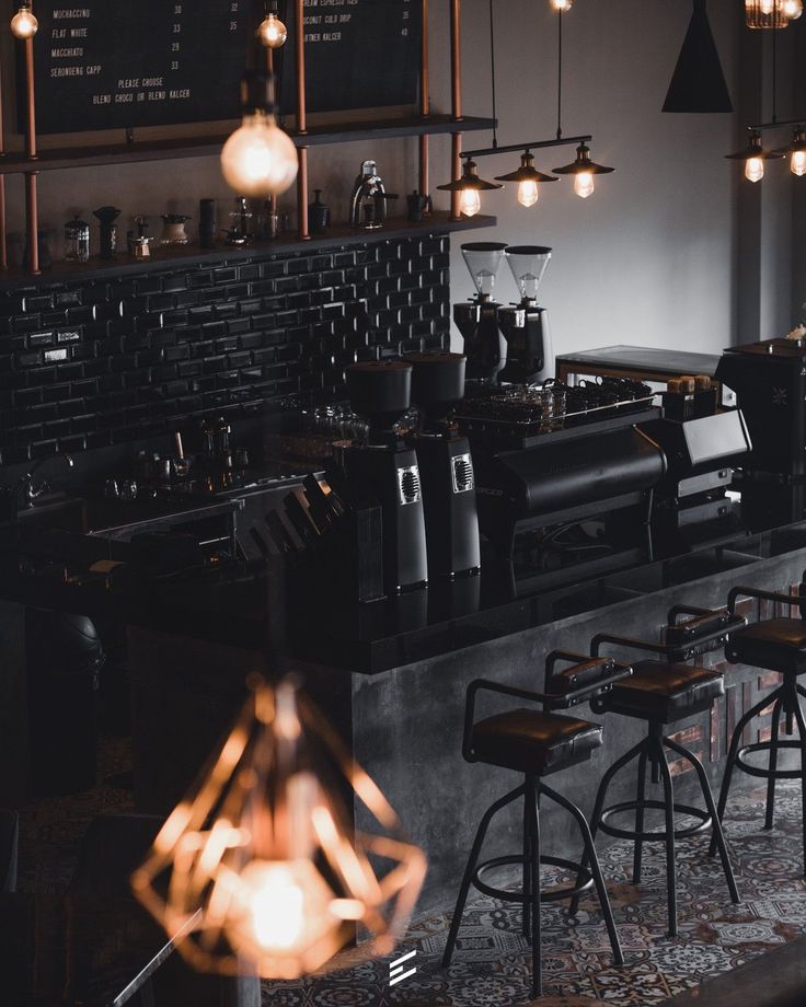 an empty bar with stools and lights hanging from the ceiling