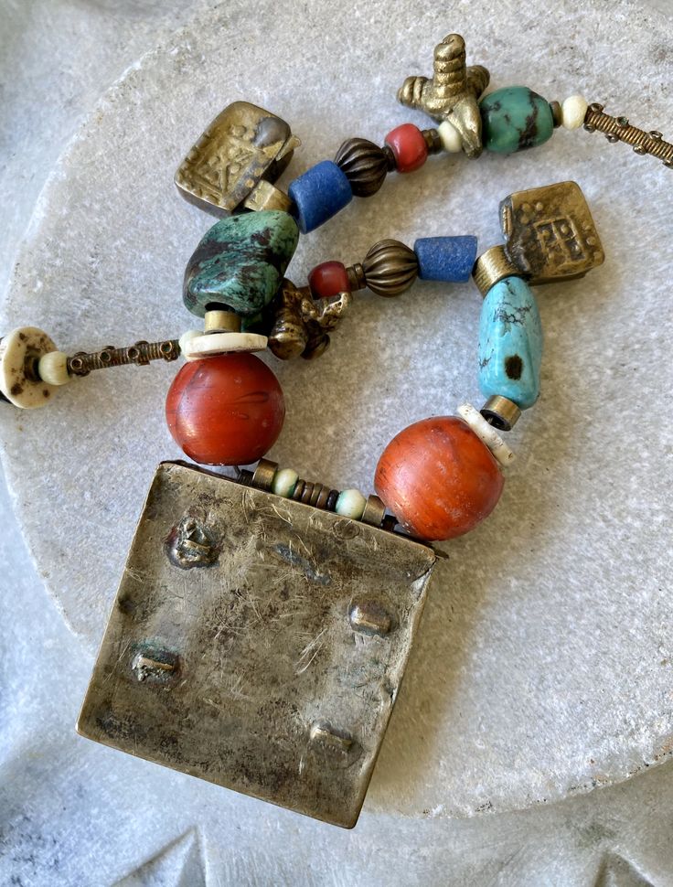 Ethnographic Antique Amulet Prayer Box Glass Brass Mixed Stone Turquoise Wood Trbal Bead Necklace measures 22 inches around weighs 3.4 oz. Ceremonial Multicolor Large Beads Jewelry, Traditional Rectangular Necklace For Festivals, Handmade Bohemian Rectangular Jewelry, Bohemian Multicolor Rectangular Jewelry, Traditional Adjustable Rectangular Necklaces, Traditional Adjustable Rectangular Necklace, Bronze Beaded Necklaces With Large Beads For Gift, One Of A Kind Artisan Rectangular Jewelry, One Of A Kind Rectangular Artisan Jewelry