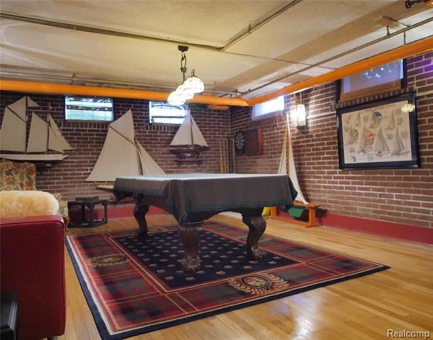 a pool table in the middle of a living room with chairs and lamps hanging from the ceiling