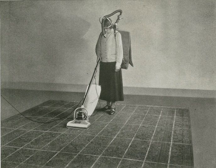 an old black and white photo of a woman with a vacuum