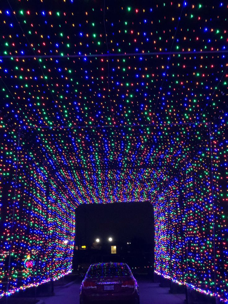 a car driving through a tunnel covered in christmas lights