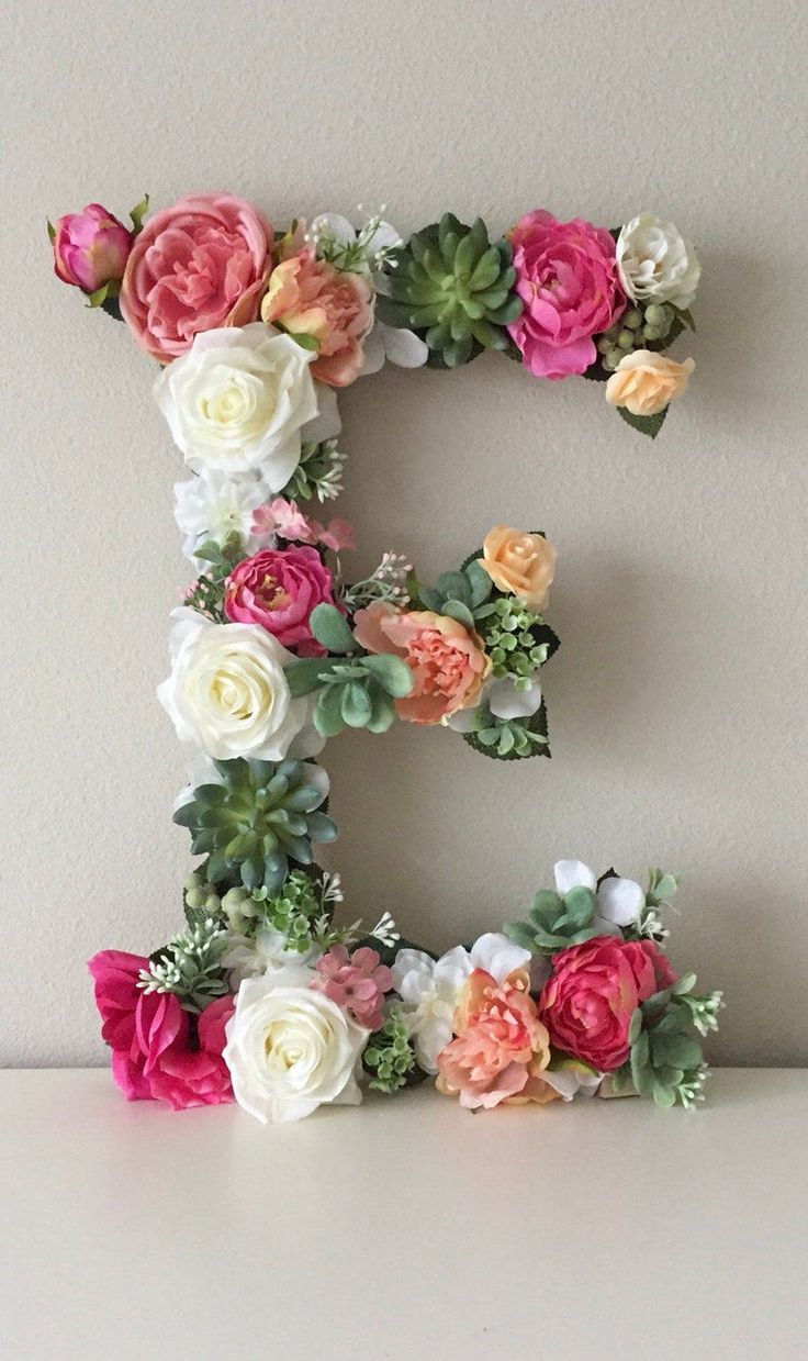 the letter e is made up of flowers and greenery on top of a table