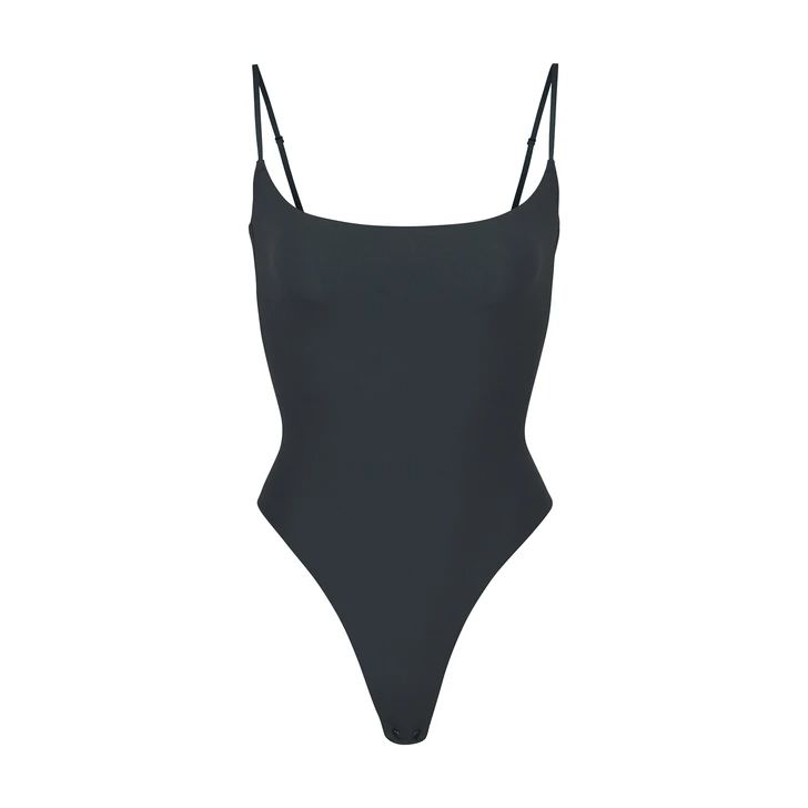 This Cami Bodysuit features a wide scoop neckline and low back providing the perfect foundation under clothing. This piece includes a thong back for seamless wear. Chic Scoop Back Swimwear For Summer, Sleek Bodysuit With Scoop Back For Swimming, Scoop Neck Swimwear With Built-in Bra, Elegant Scoop Back Swimwear For Beach, Chic Scoop Back Swimwear For Poolside, Chic Poolside Scoop Back Swimwear, Elegant Scoop Neck Summer Bodysuit, Sleek Scoop Back Swimwear For Summer, Sleek Bodysuit With Moderate Back Coverage For Poolside