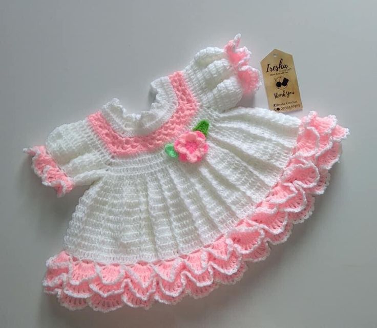 a crocheted baby dress with pink flowers on it