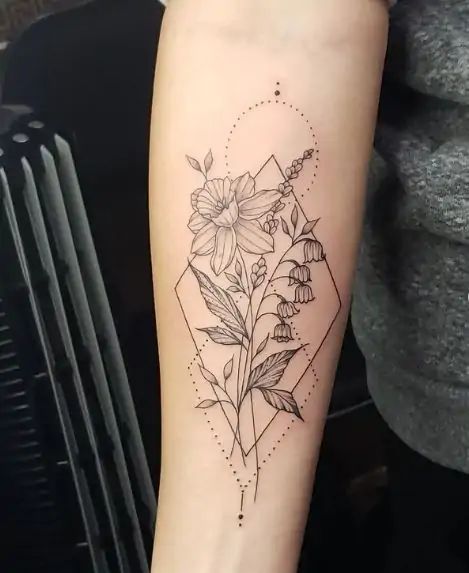 a black and white photo of a flower tattoo on the right arm, with geometric shapes in the background