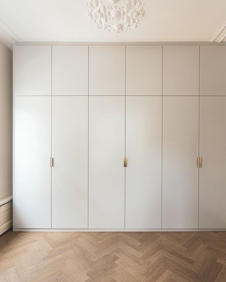 an empty room with white cupboards and a chandelier