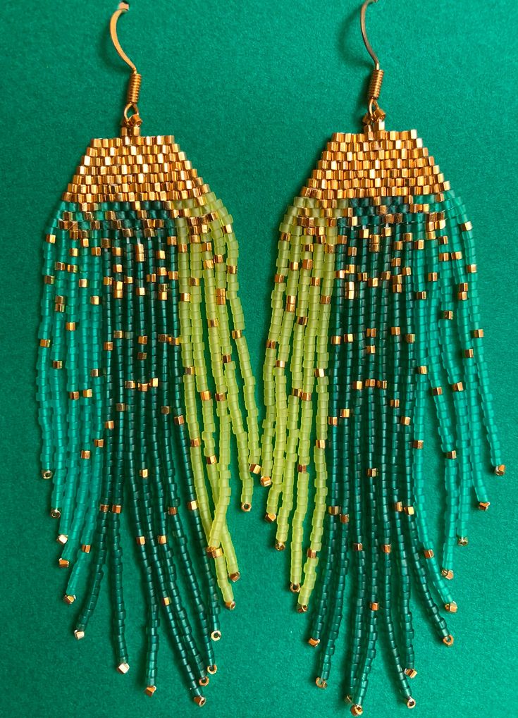 Gold beads sparkle and shimmer as they catch the light.   24 kt gold cut beads with teal, emerald and chartreuse translucent beads.  Inspired by the myriad greens and stars of tropical nights.  Handmade with love by me. 4" long 1.25" wide Green Beaded Earrings With Dangling Beads For Celebrations, Green Beaded Dangling Earrings For Celebration, Green Dangle Beaded Earrings With Gold Beads, Bohemian Green Earrings With Gold Beads, Green Dangling Beads Earrings For Celebration, Green Beaded Emerald Jewelry, Green Beaded Dangling Earrings For Party, Green Beaded Dangle Earrings For Celebration, Green Beaded Dangle Earrings For Festive Occasions