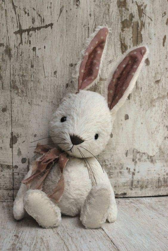 a white stuffed rabbit sitting on top of a wooden floor next to an old wall